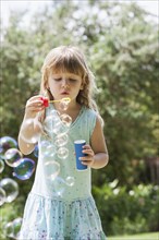 Caucasian girl blowing bubbles outdoors