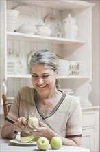 Caucasian woman peeling fruit in kitchen