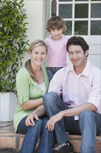 Caucasian family smiling on front steps