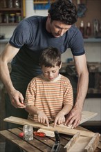 Caucasian father and son working in woodshop