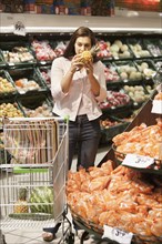 Caucasian woman smelling pineapple in grocery store