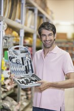 Caucasian man holding tools in hardware store