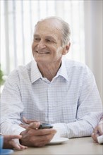 Senior Caucasian man using cell phone in cafe
