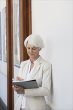 Senior Caucasian businesswoman making notes in office