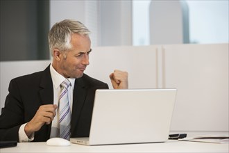 Businessman cheering at desk in office