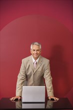 Businessman with laptop standing at conference table