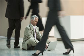 Businessman using laptop on busy office floor