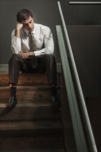 Stressed businessman sitting on stairs