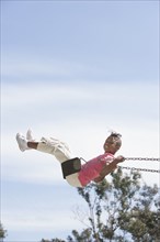 African American girl playing on swing
