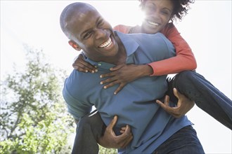 Man carrying girlfriend piggyback in park