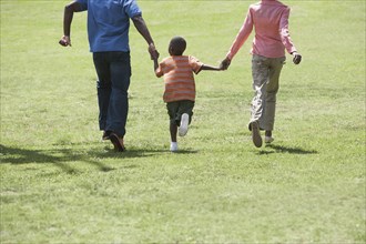 Boy holding parents' hands in park