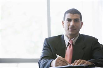 Hispanic businessman making notes in office