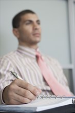 Hispanic businessman taking notes in office