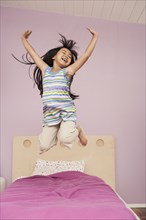 Chinese girl jumping on bed
