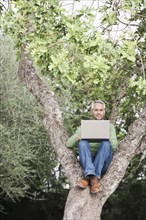 Man using laptop in tree