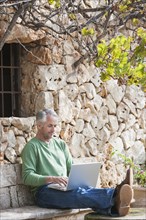 Man using laptop in backyard