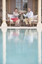 Couple toasting each other by swimming pool