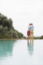 Couple standing by infinity pool