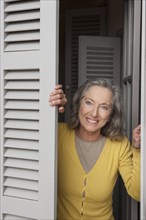 Woman peering out window shutters