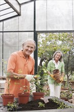 Couple potting plants in greenhouse