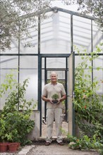 Man holding plants in greenhouse