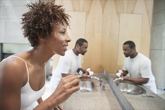 African American couple brushing teeth in bathroom
