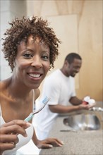 African American woman brushing teeth in bathroom