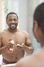 African American man shaving in bathroom
