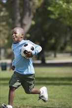 African American boy playing soccer in park