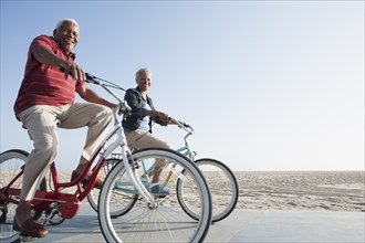 Senior African American couple riding bicycles by beach