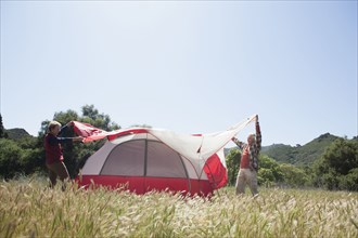 Senior Caucasian couple pitching tent in field