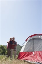 Senior Caucasian couple admiring tent in field