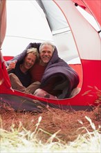Senior Caucasian couple in sleeping bag in tent