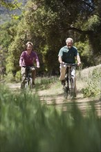 Senior Caucasian couple riding bicycles on rural path