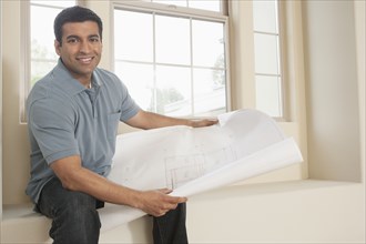 Hispanic man reading blueprints in new home