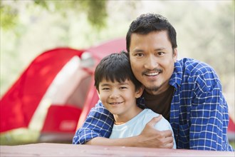 Asian father and son hugging outdoors