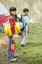 Children carrying camping gear outdoors