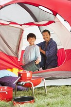 Asian father and son unpacking in tent
