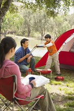 Asian family relaxing at campsite