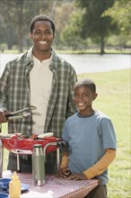 Father and son cooking at picnic table