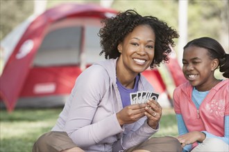 Mother and daughter playing cards at campsite