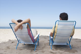 Couple relaxing in lawn chairs on beach