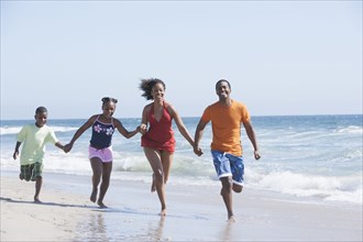 Family running in waves on beach