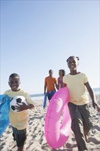 Children carrying inner tubes on beach