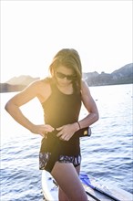 Caucasian woman fastening belt near paddleboard