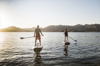 Couple standing on paddleboards in rover