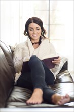Caucasian woman sitting on sofa reading book