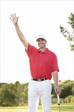 Hispanic golfer waving on golf course