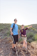 Couple hiking on hill holding walking sticks