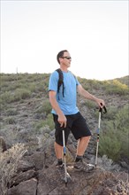 Hispanic hiker holding walking sticks on hill